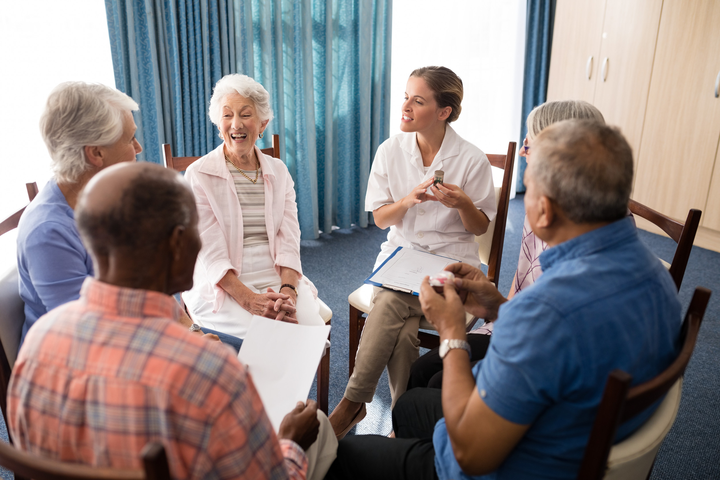 High angle view of smiling female doctor talking to seniors while sitting on chairs High angle view of smiling female doctor talking to seniors while sitting on chairs